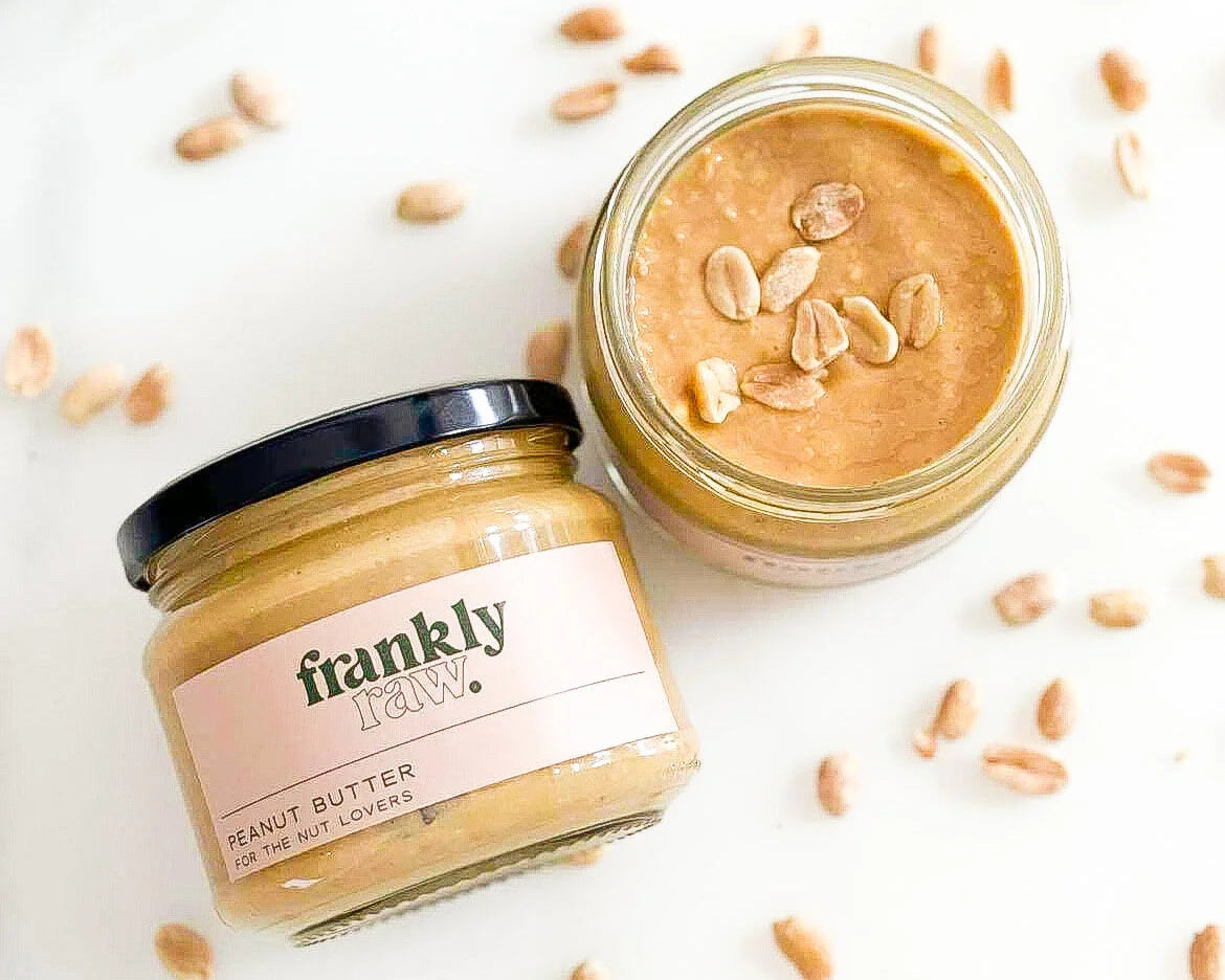 Two jars of Frankly Peanut Butter on a white background with scattered peanuts.